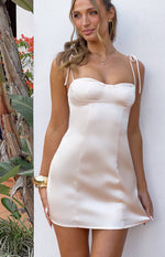 Cream satin mini dress with a sweetheart neckline, bustier cups, and delicate tie-up spaghetti straps
