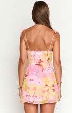 Back view of a pink and yellow floral mini dress with a straight back, fitted waist, and delicate tie-up shoulder straps