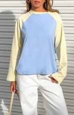 Front view of a blue and yellow contrast raglan sleeve top with a relaxed fit and crew neckline