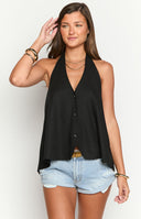Model wearing a flowy black halter top with a deep V-neck and low back