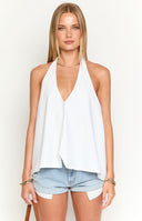 a brunette model wears a white button up top, sunglasses and denim mini skirt holding a drink