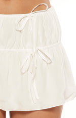 Close-up of the white mini skirt's tied drawstring waist and horizontal ruched band detail