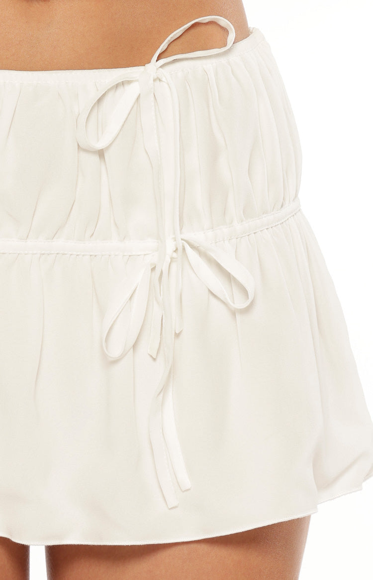 Close-up of the white mini skirt's tied drawstring waist and horizontal ruched band detail