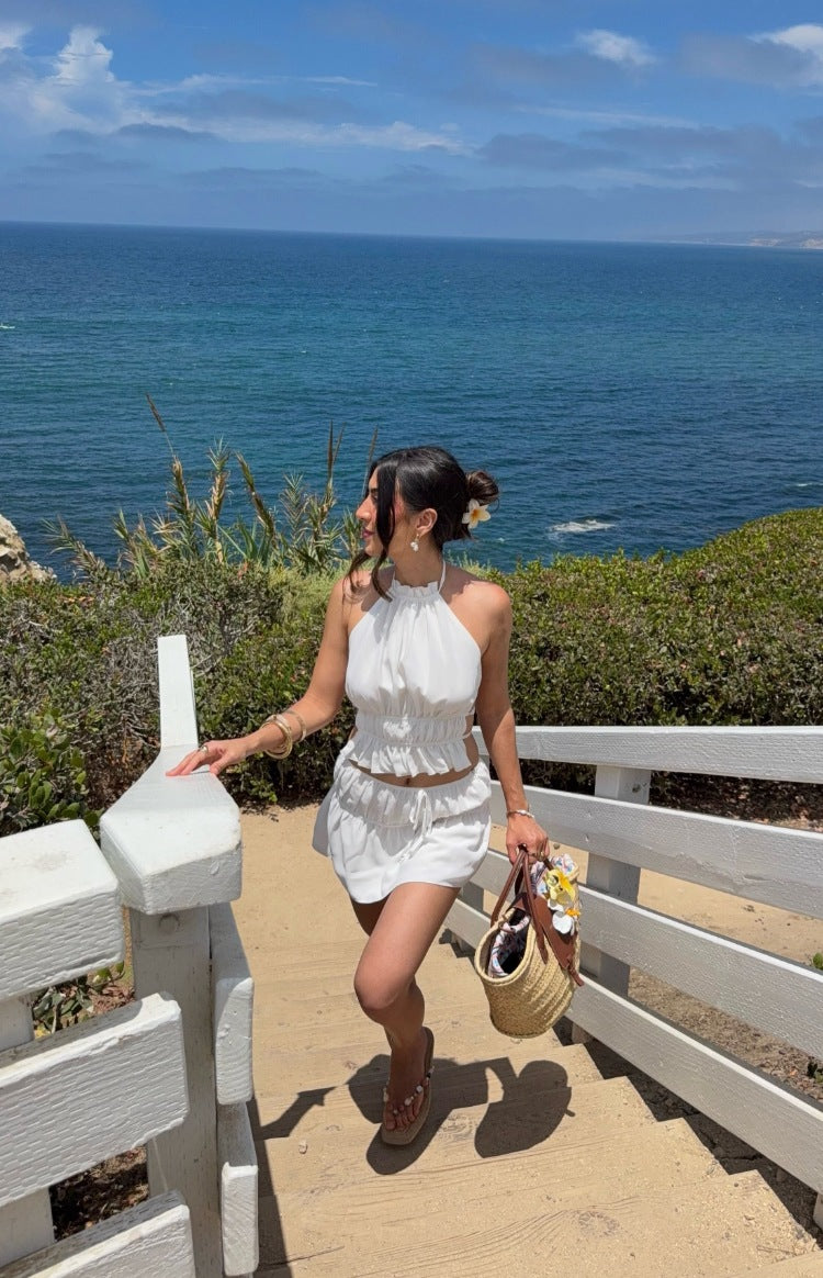 White ruched mini skirt with tiered ruffle details and a drawstring waist, showing its relaxed fit