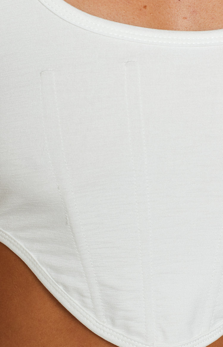 White textured knit corset top with visible vertical boning seams and curved hemline