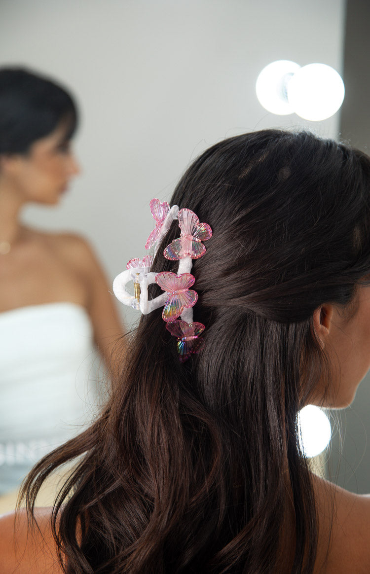 Side view of the white claw clip with three iridescent pink butterflies, highlighting the textured wings and subtle shimmer