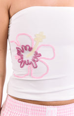 Close-up of the white strapless top featuring a pink, fuchsia, and cream beaded hibiscus flower design
