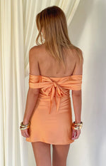 Rear view of an orange satin off-shoulder mini dress featuring a large tie-back bow