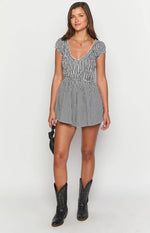 Front view of a black gingham playsuit featuring a shirred bodice and waist with flared shorts