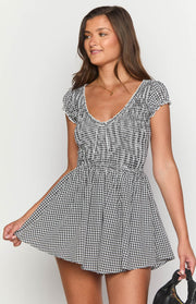 V-neck black gingham playsuit with a shirred bodice, white tie detail, and ruffled short sleeves