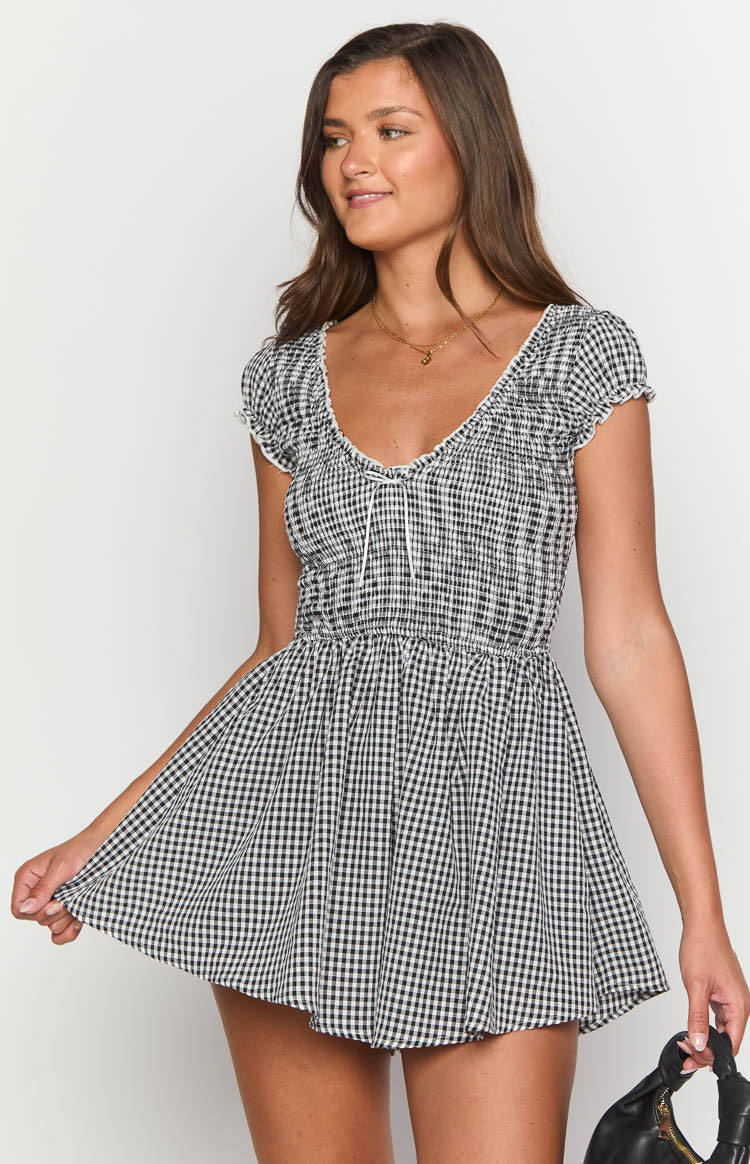 V-neck black gingham playsuit with a shirred bodice, white tie detail, and ruffled short sleeves