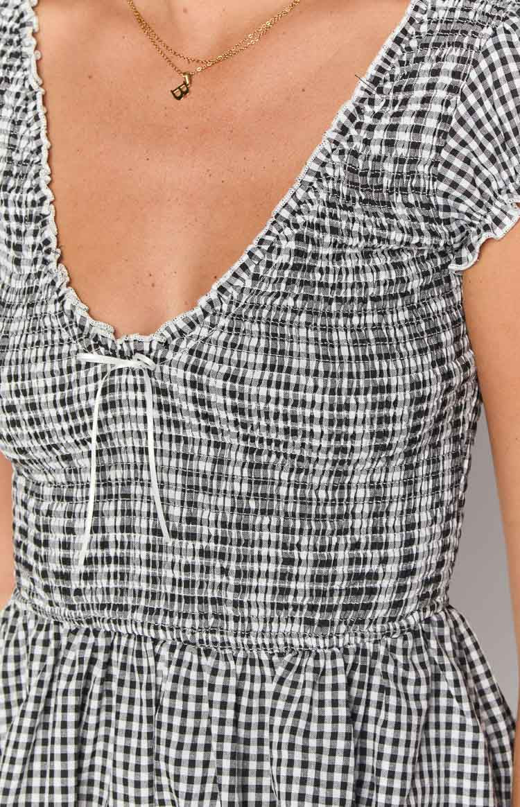 Close-up of the black gingham playsuit showing the shirred bodice with a white tie V-neckline