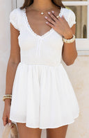 White playsuit with a shirred bodice, ruffled V-neckline, and short puff sleeves