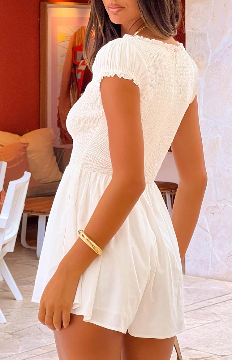 Side view of a white playsuit showing the smocked bodice, ruffled short sleeves, and flowy shorts