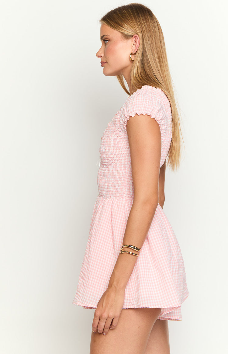 Side view of a pink gingham playsuit with a smocked bodice, short puff sleeves, and flared shorts