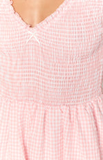 Pink gingham playsuit with a shirred bodice, ruffled V-neckline, and tiny white bow detail