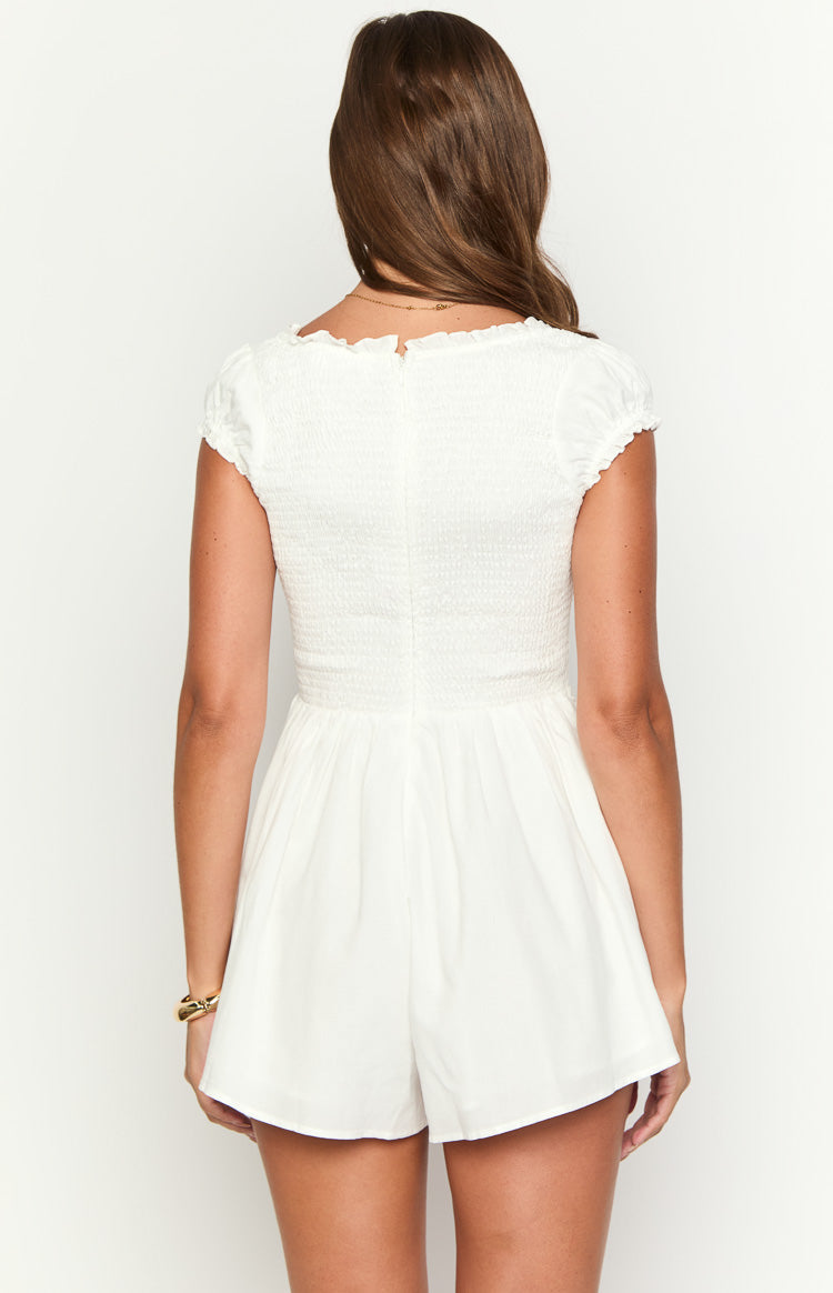 Rear view of a white playsuit with a smocked bodice, ruffled neckline, short puff sleeves, and keyhole back closure