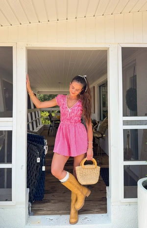 Full view of a red gingham playsuit with a V-neck, white lace trim, puff sleeves, and a shirred waist