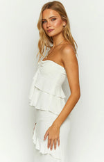 Side view of a white strapless top with tiered ruffles, ruched bust detail, and a visible side zipper