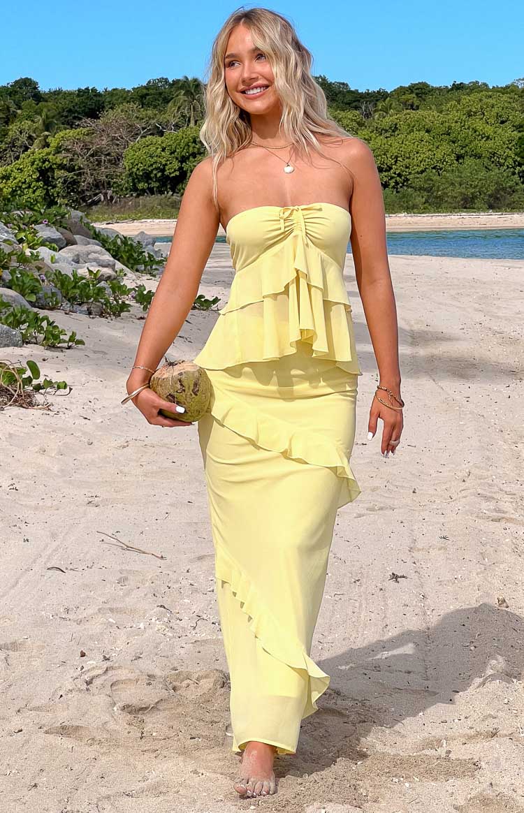 Front view of a yellow strapless top with a ruched bust and tiered ruffles creating a peplum silhouette