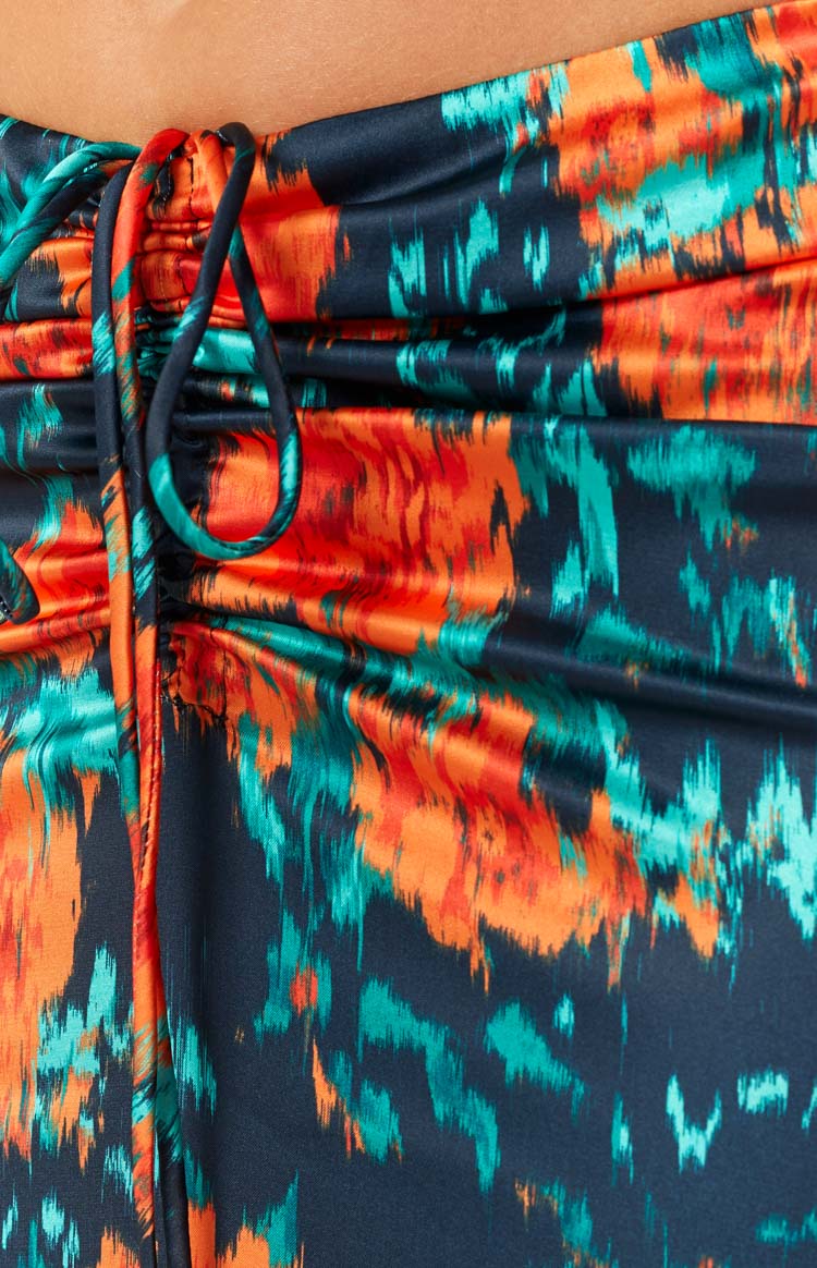 Rear view of a fitted dark blue maxi skirt with a vibrant orange and teal floral pattern