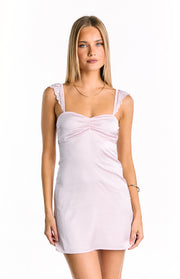 Front view of a light pink mini dress with a ruched sweetheart neckline and lace trim on the shoulder straps