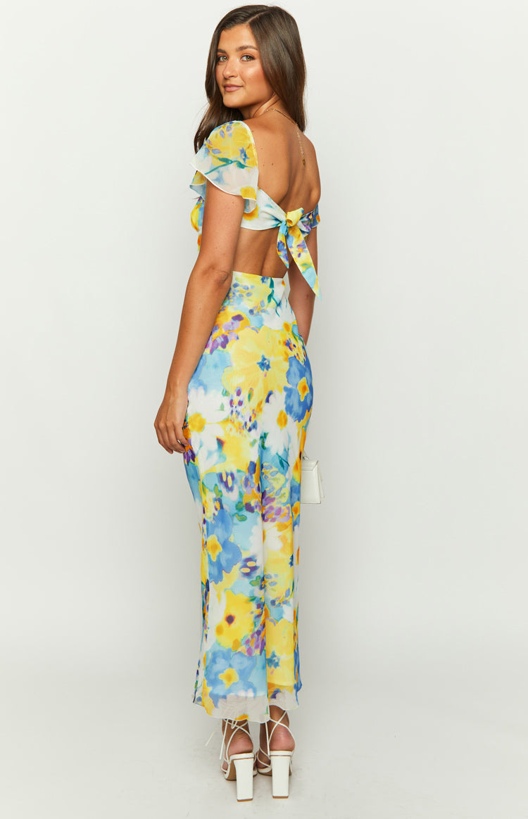 Rear view of a blue and yellow floral chiffon maxi dress with an open back and tie-up bow detail