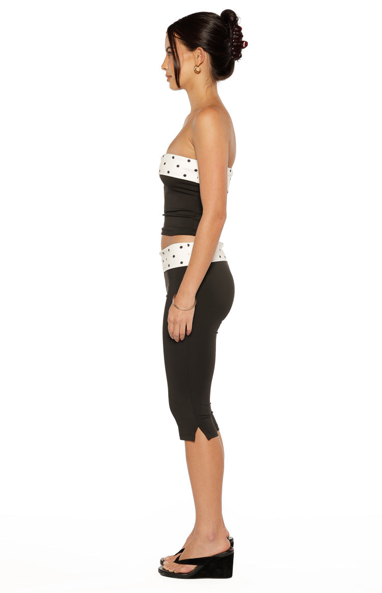 Side view of the black strapless top with a white band featuring black polka dots, showing its fitted silhouette