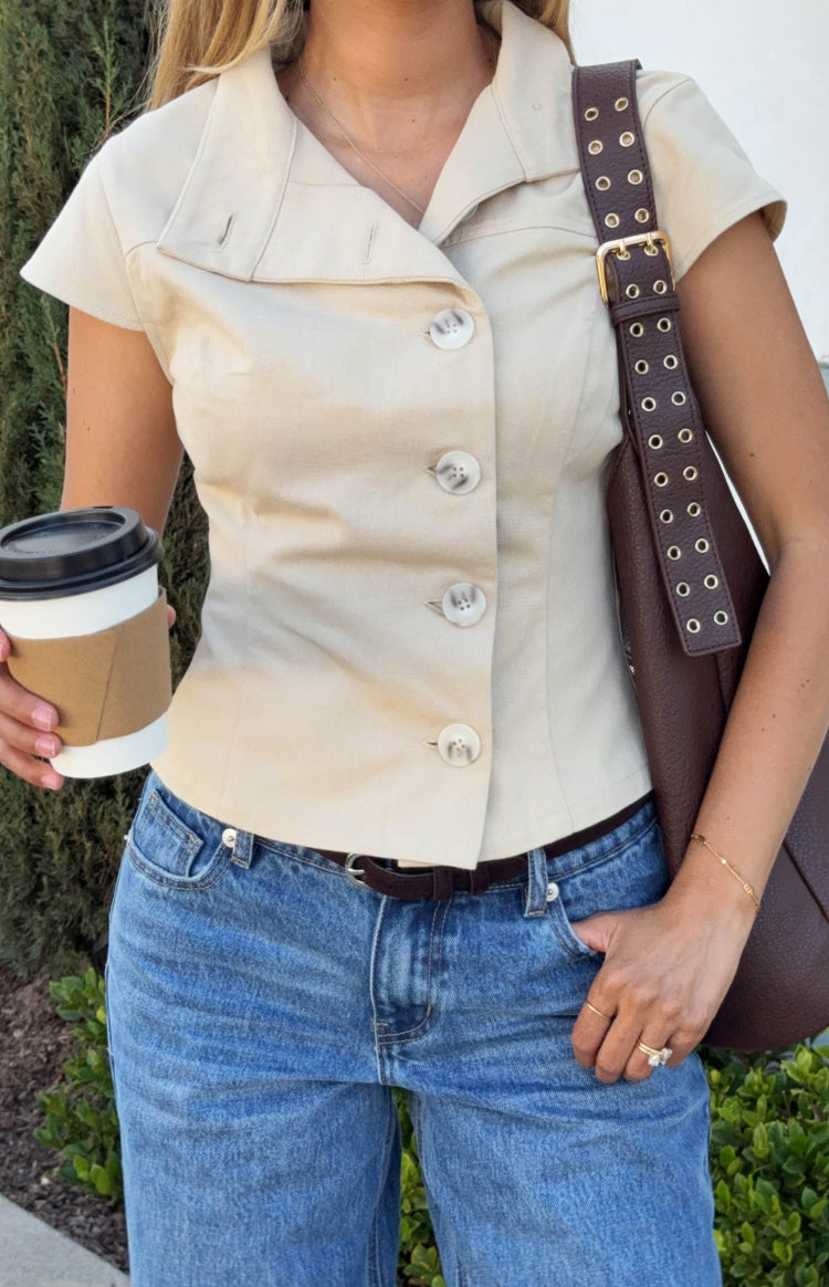 Close-up of the beige top's button-front closure and distinctive wide folded collar