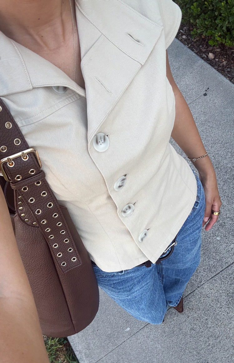 Top-down view of a beige button collar top with a diagonal button-front closure and structured fabric