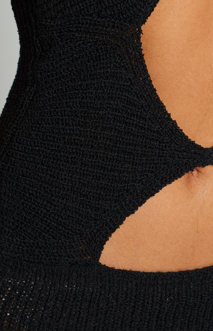 Front view of a black ribbed knit midi dress with halter neckline, large chest and midriff cutouts, and a thigh-high split