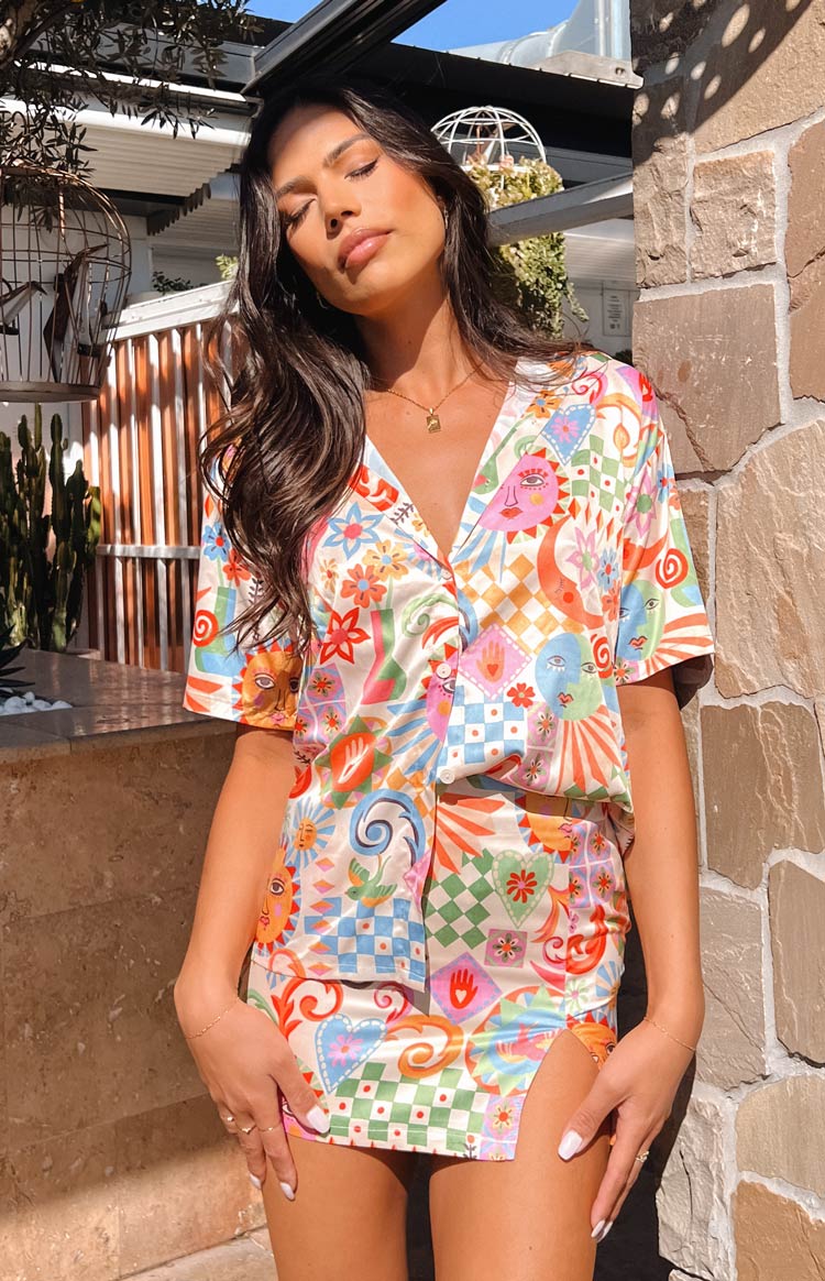 Multi-colour satin mini skirt with a vibrant psychedelic print featuring a high side slit