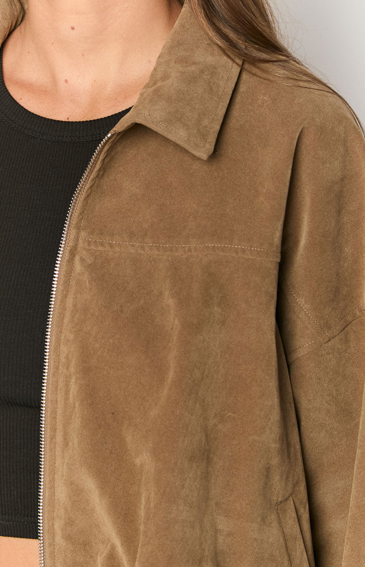 Close-up of the brown suedette bomber jacket's silver zipper, pointed collar, and chest stitching