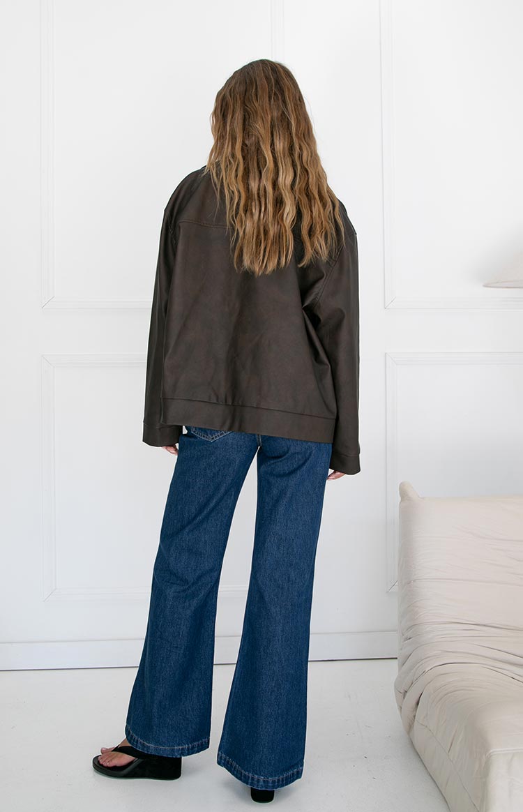 Rear view of a chocolate brown oversized PU biker jacket with wide shoulders and a straight hem