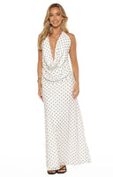 A studio shot from the neck to the waist of our model wearing a white halter top with a small black polka-dot pattern. This garment features a deep draped cowl neckline and is styled tucked into high-waisted black bottoms.