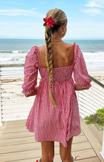 Rear view of a red gingham babydoll mini dress with a square back neckline and smocked bodice