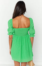 Rear view of a green checkered babydoll mini dress with a square back neckline, shirred bodice, and puffed sleeves