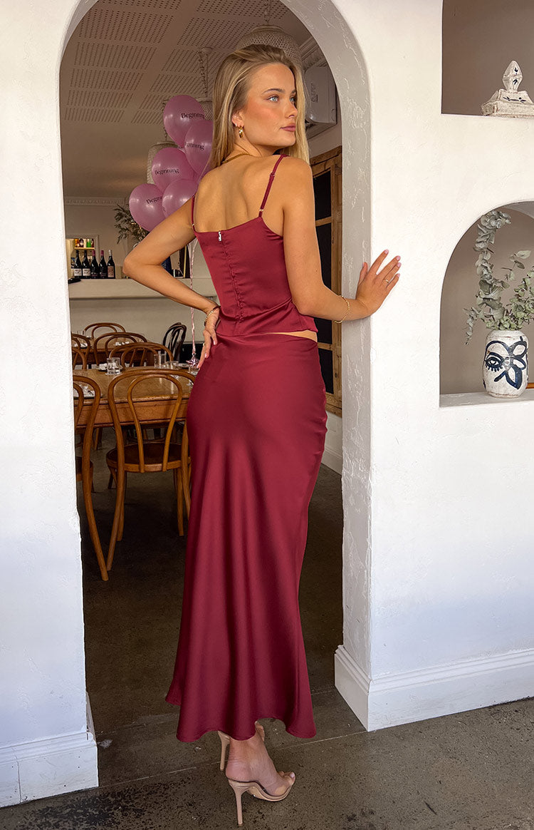 Side view of a burgundy satin maxi skirt with a fluid, flowing silhouette