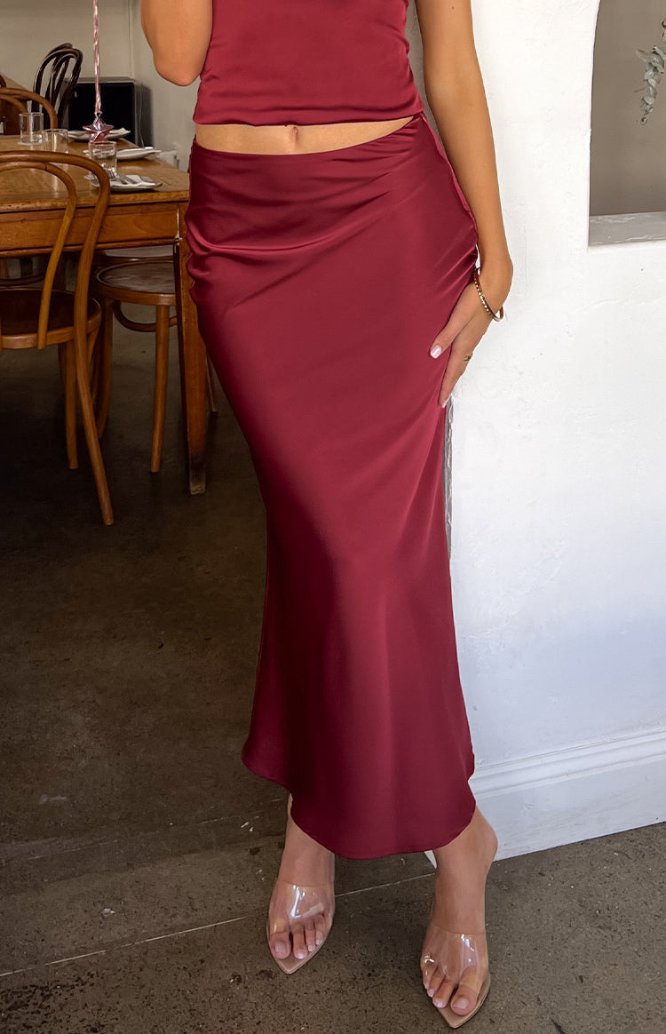 Burgundy satin maxi skirt with a draped detail at the waist and a flowing silhouette