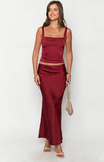 Full length view of a burgundy satin maxi skirt with a fitted waist and flowing silhouette