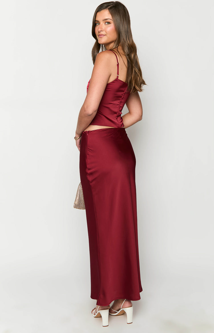 Side view of a burgundy satin maxi skirt showing the flowy fit and side zipper closure