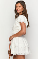 Side view of a white mini dress with tiered eyelet lace skirt and flutter sleeves