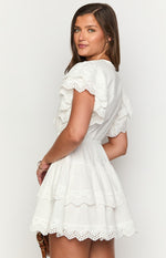 Side view of a white mini dress with ruffled broderie anglaise sleeves and a tiered skirt with matching trim