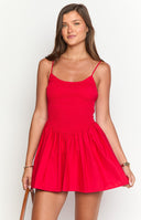 Blonde model is wearing a bright red mini dress. Her hair is in a messy bun and is wearing gold jewellery.