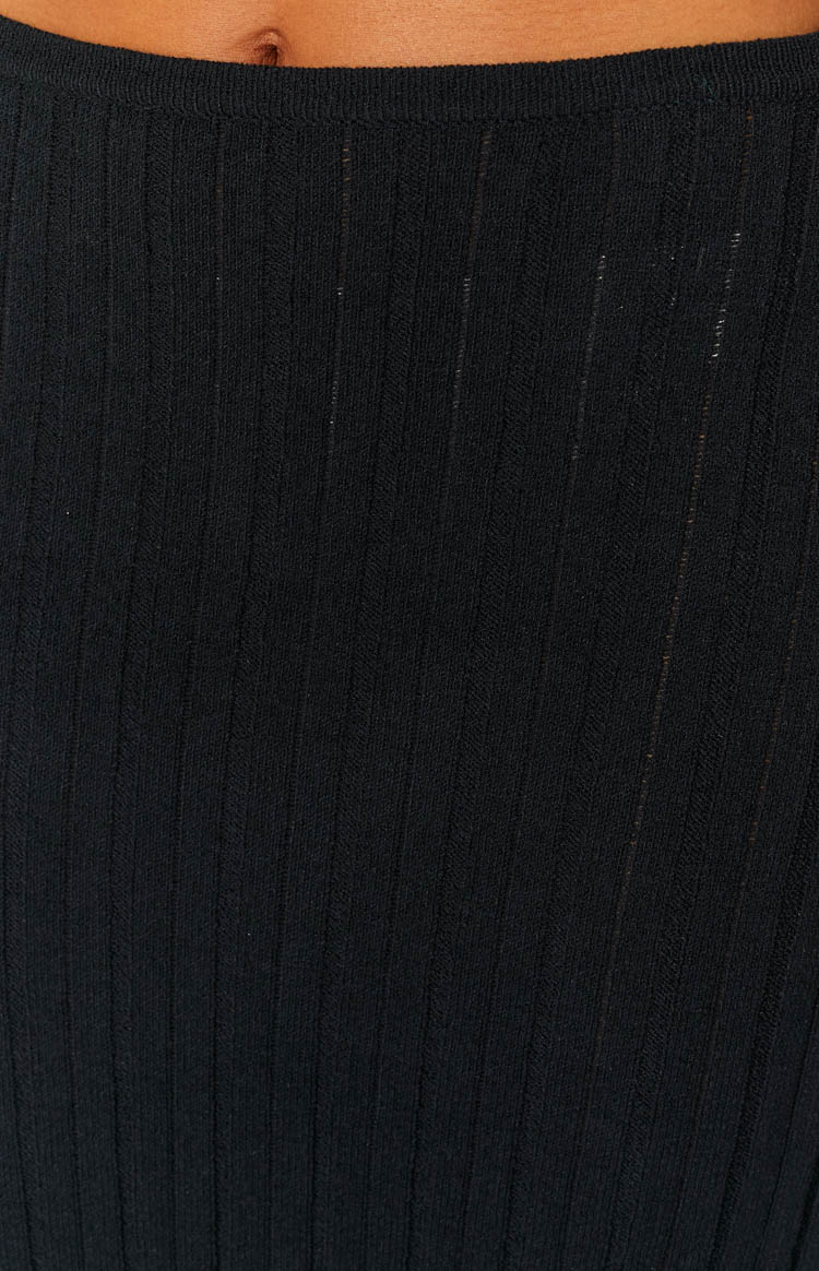 Close-up of the black ribbed knit texture of the skirt with a simple finished waistband