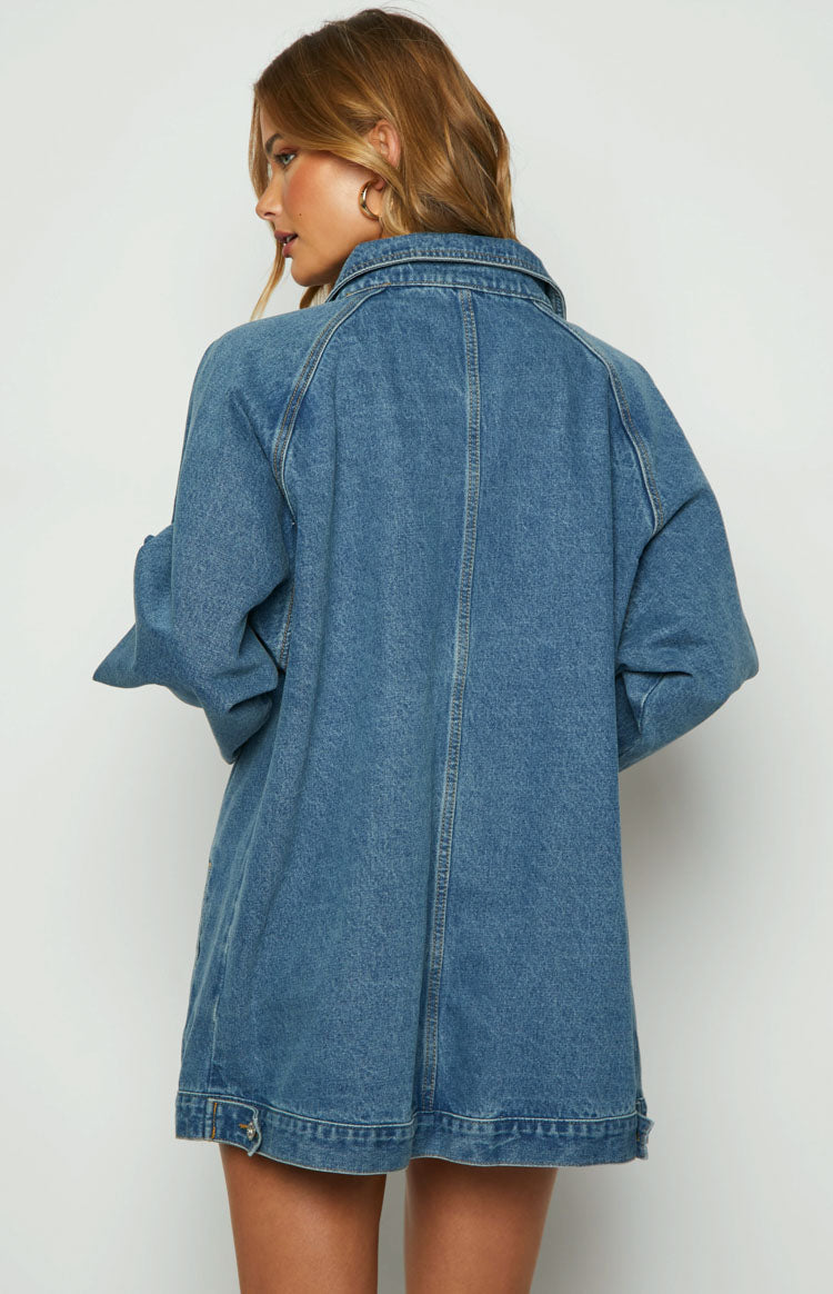 Side view of a blue oversized denim jacket with a collar, long sleeves, and a vertical front pocket detail