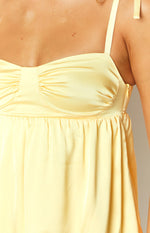 Detail shot of the yellow satin mini dress showing the ruched bust, gathered waist, and side zipper