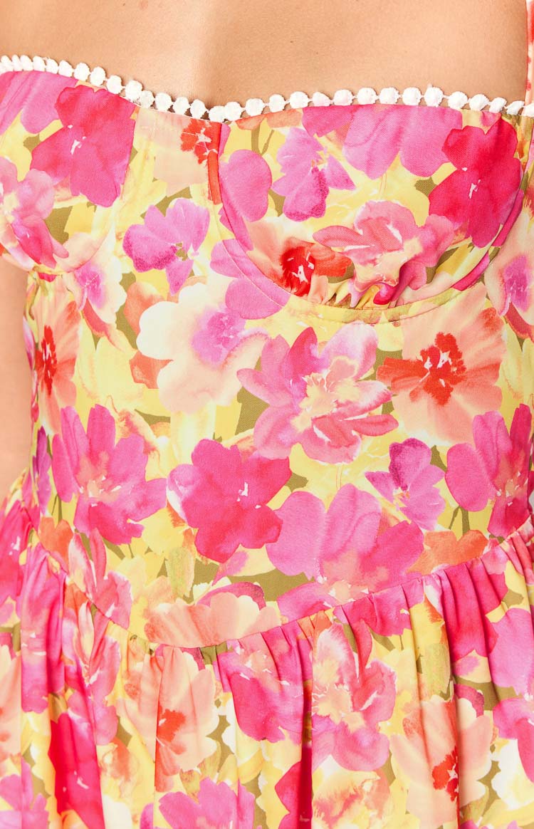 Close-up of the upper bodice of the yellow floral mini dress, with sweetheart neckline, white pom-pom trim, and bustier-style seaming
