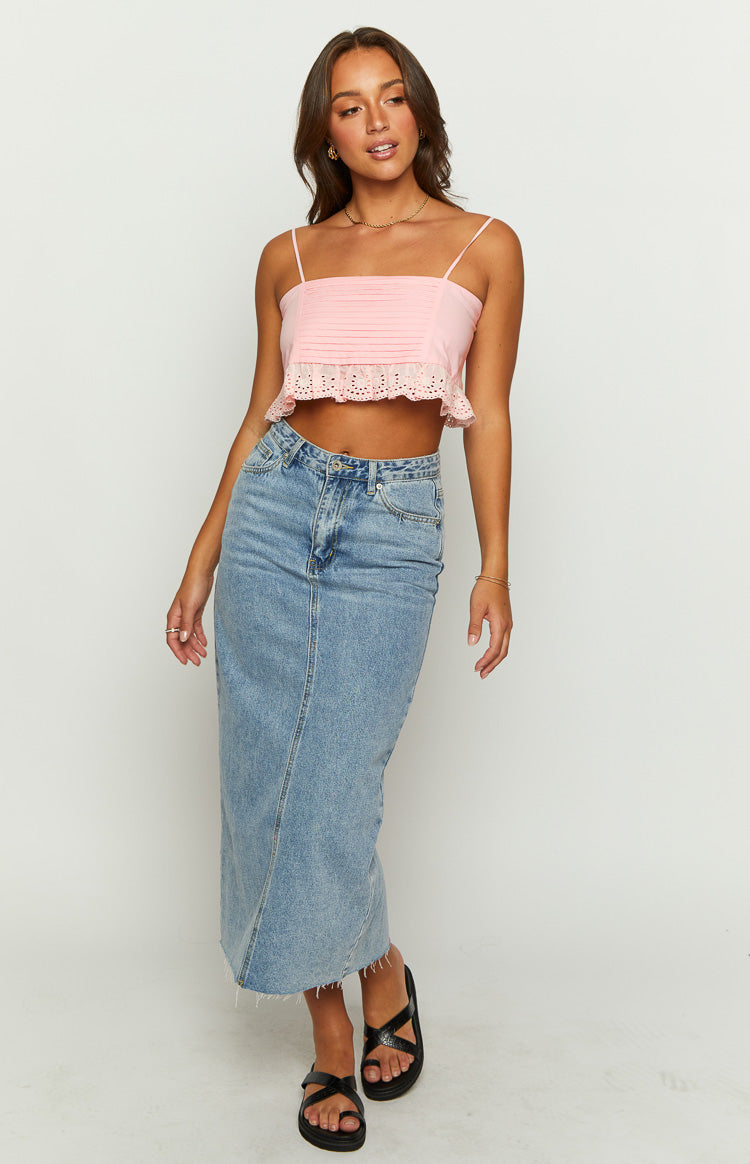 Pink crop top with a straight neckline, thin spaghetti straps, pleated bust, and a ruffled eyelet lace hem