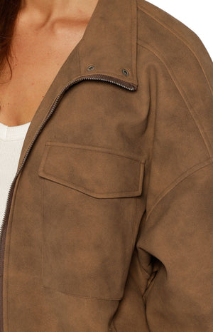Close-up of the brown suedette jacket showing the funnel neck, zipper, snap buttons, and chest pocket